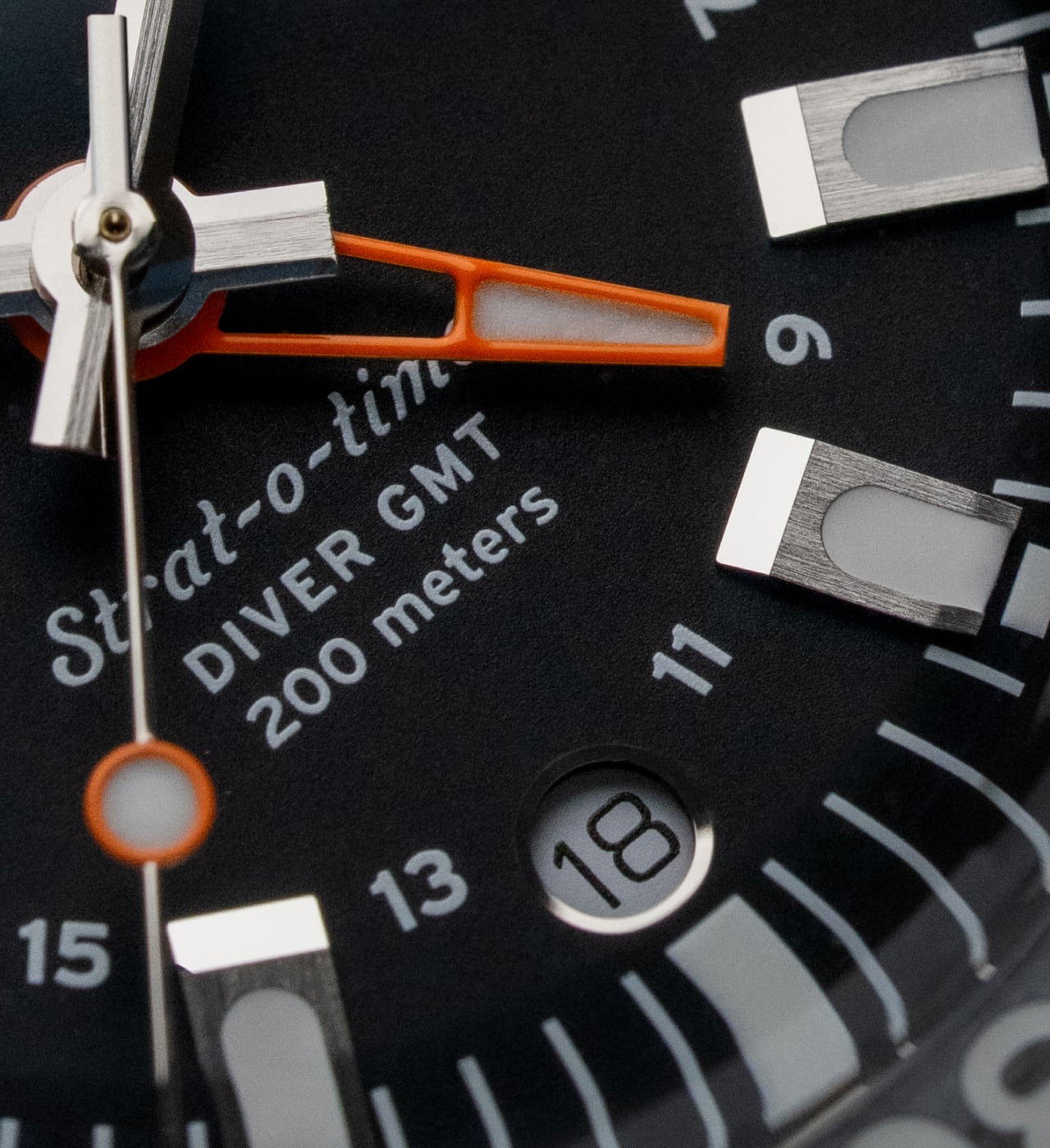 The raised markers and orange GMT hand in another dial detail.